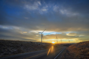 wind turbines along desert road at sunset