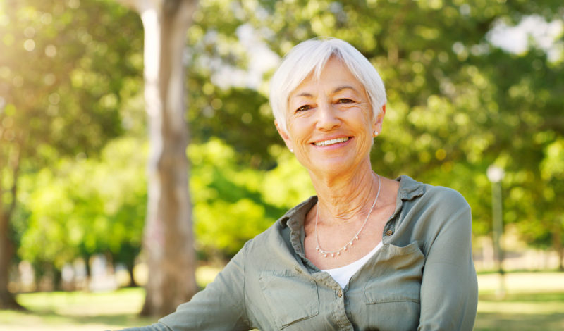 older woman smiling while sitting in park